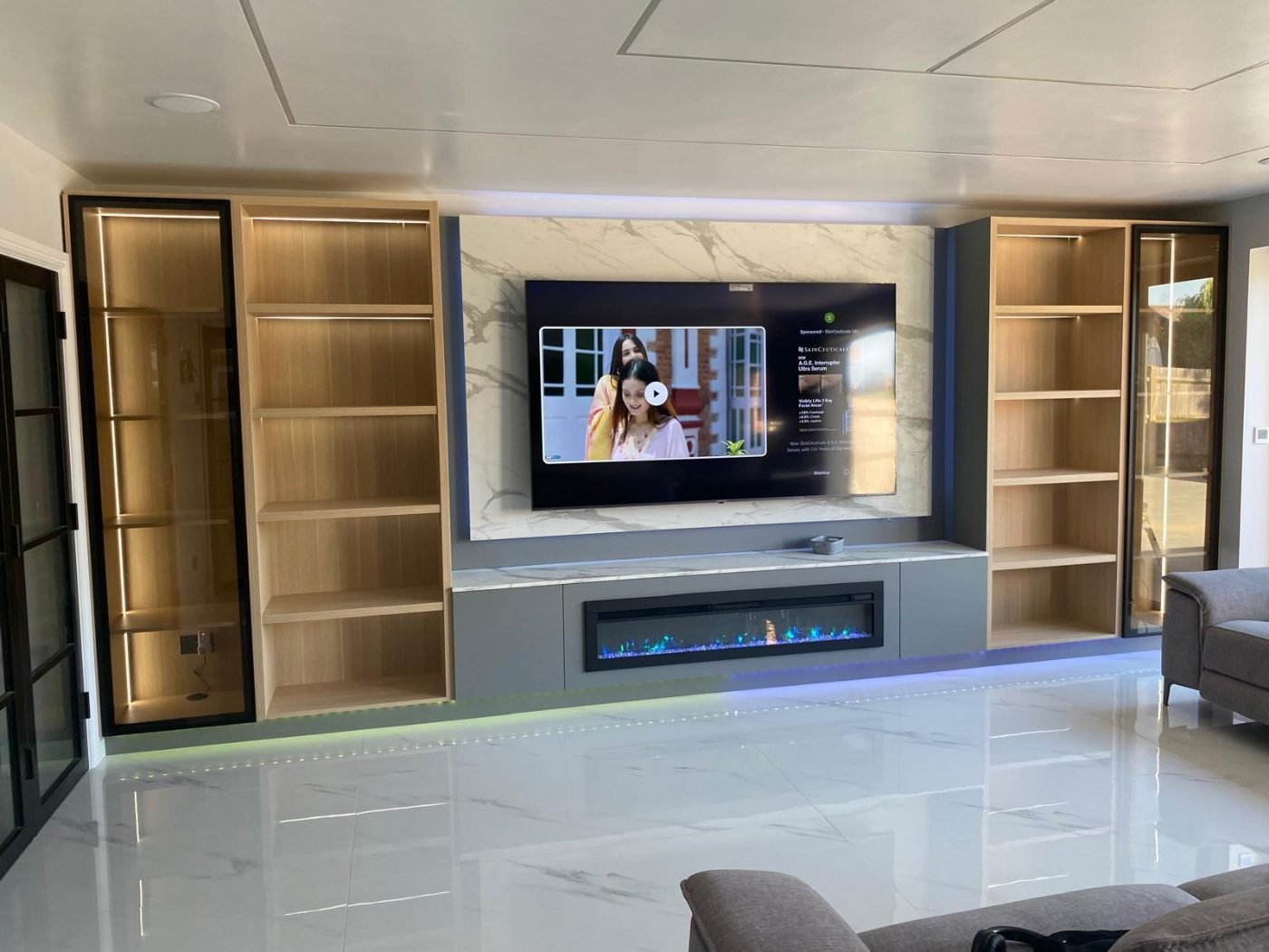 Media wall with lit oak shelving and electric fire by Kulwant Carpentry